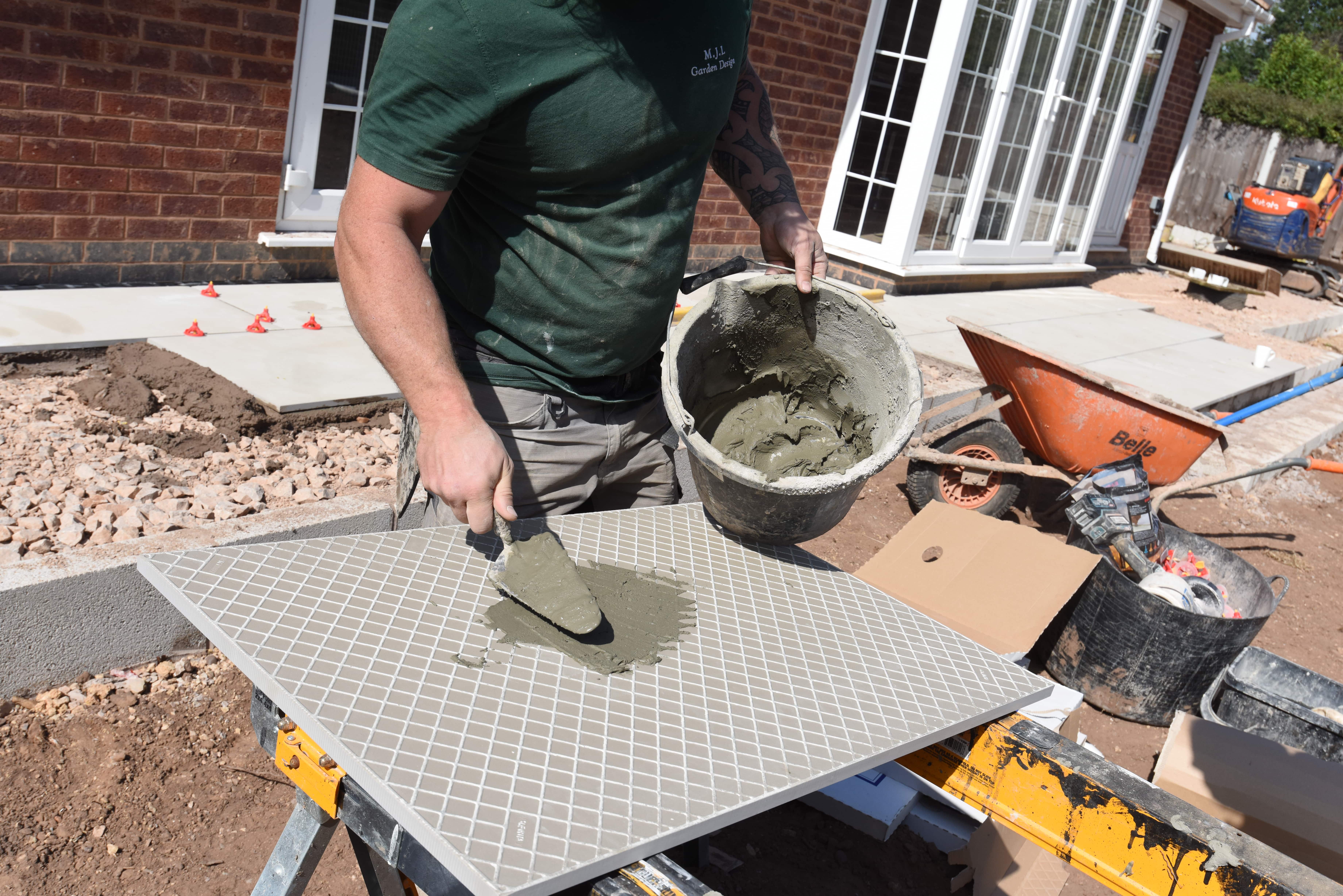 Primer being applied on the back of a porcelain paving tile with a trowel